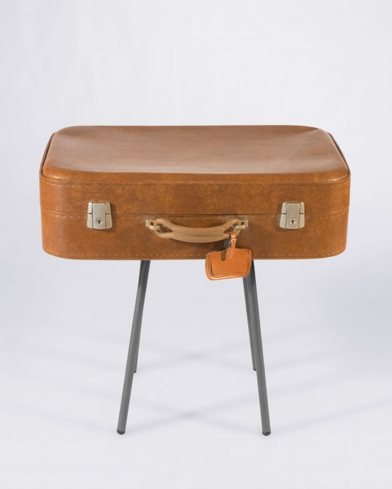 Mesa vintage compuesta por cuatro patas metálicas y una antigua maleta de piel color camel